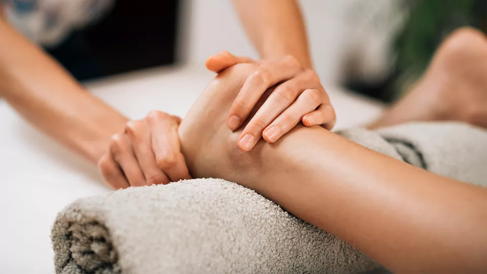 Démonstration d'un massage doux du pied et de la cheville lors d'un module de formation en réflexothérapie Ortra TC.