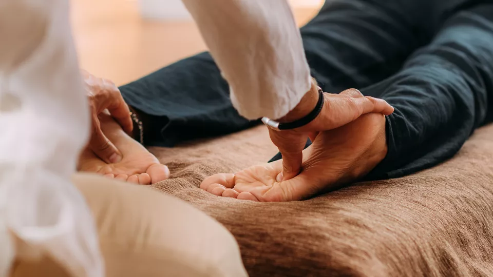 Pratique du Shiatsu : démonstration d'une pression précise des pouces sur la voûte plantaire d'un patient lors d'une formations Ortra TC.